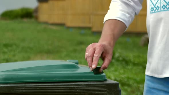 A Man's Hand Throws a Plastic Bottle Into a Recycling Container