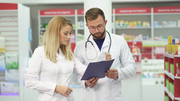 Two Pharmacists Are Discussing Medication Working in Pharmacy.