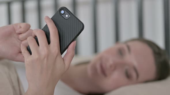 Young Woman in Blur Using Smartphone in Bed