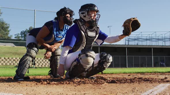 Diverse group of female baseball players in action, pitched ball caught by catcher and returned