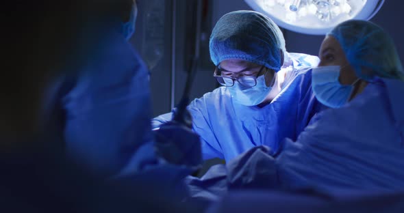 Diverse surgeons wearing face masks and protective clothing in operating theatre