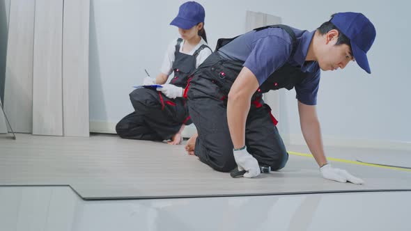 Asian Craftsman worker people renovate and installs laminate board on floor at apartment or house.