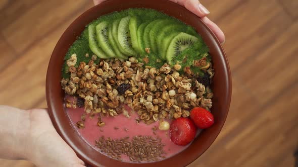 Woman Holds a Bowl of Smoothies with Strawberry Seeds Kiwi Granola