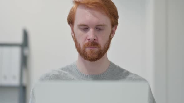 Young Beard Redhead Man Using Laptop