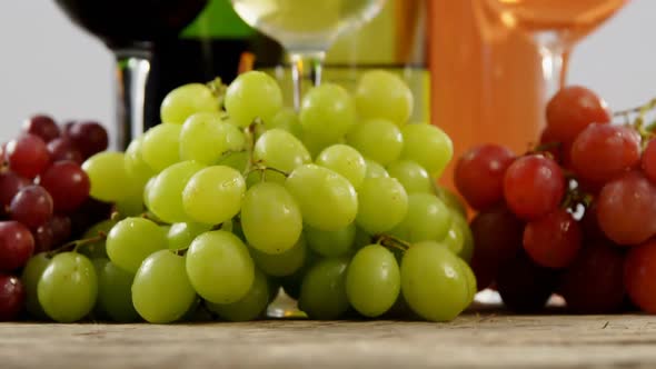 Various grapes and wines on wooden plank