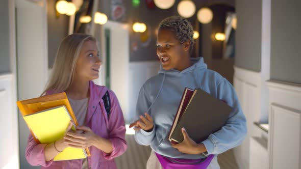 Young Student Friends Going To Class Walking Through University Corridor