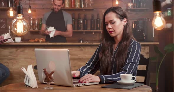 Young Creative Woman Closes Her Laptop and Leaving the Table of a Small Coffee Shop