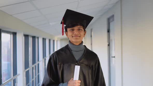 Pakistani Graduate in Mantle Stands with a Diploma in Her Hands and Smiles