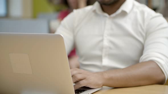 Focused Young Man Using Laptop at Library