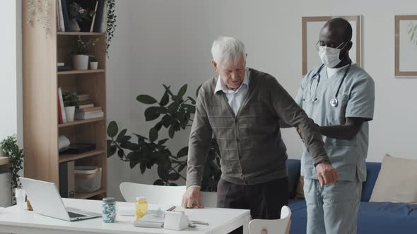 African-American Medical Worker Examining Senior Man at Nursing Home