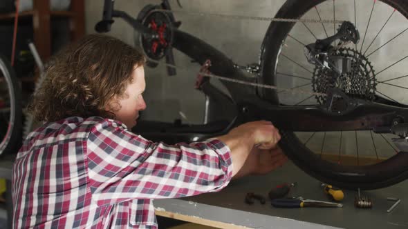 Focused caucasian man repairing bike using tools in garage