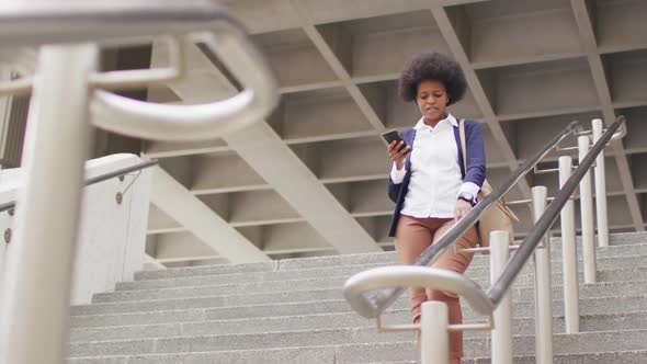 African american businesswoman walking and holding smartphone