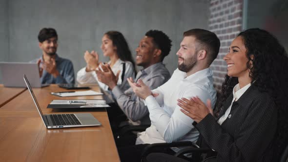 Satisfied Diverse Employees Sitting in Conference Room Listen Colleague Presentation Clap Hands in
