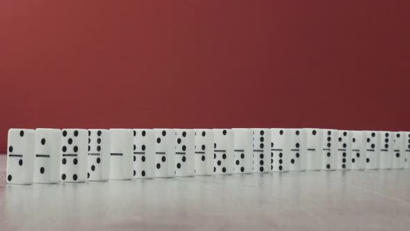 Domino Effect - a Series of White Dominoes Falling Down the Chain on Red Background