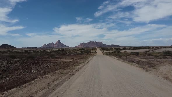 Drone footage of a long road in the desert with huge Erongo mountains