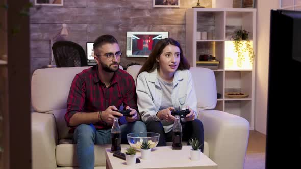 Cheerful Young Couple Sitting on Couch and Playing Video Games