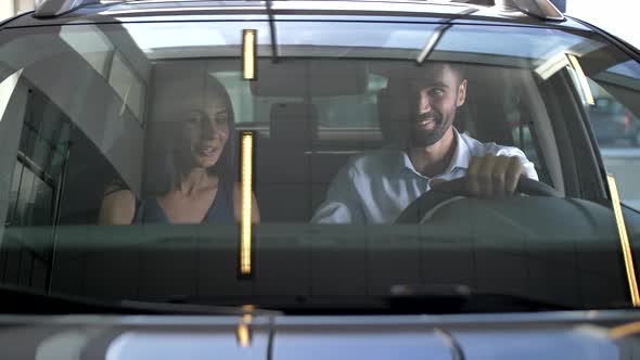 Young Couple Testing Car From Inside at Showroom