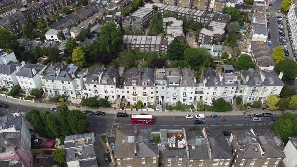 Red london bus passing row of terraced house Primrose hill London , drone aerial view