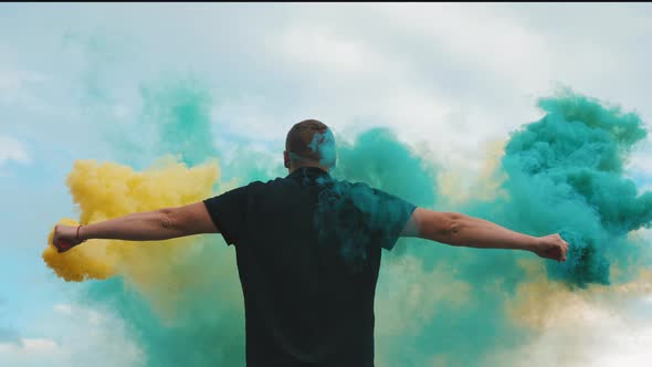 Back View of a Man with a Yellow and Blue Smoke Bomb