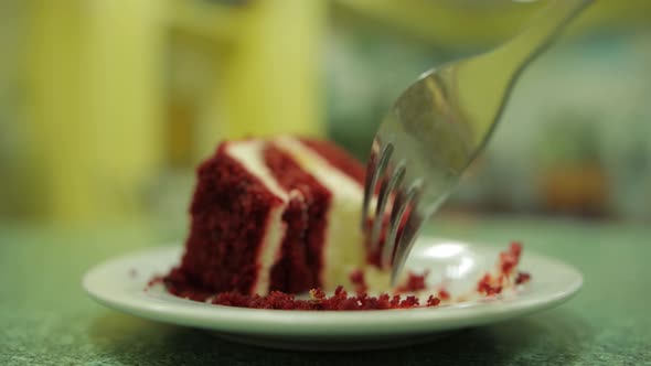 A Man Eats with a Fork a Piece of Soaked Cake with Red Cakes and Cream