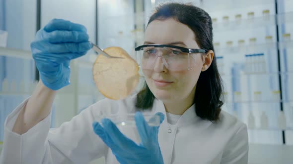 Close Up Portrait of a Woman Scientist in a White Coat with Tweezers in Her Hands Looking at