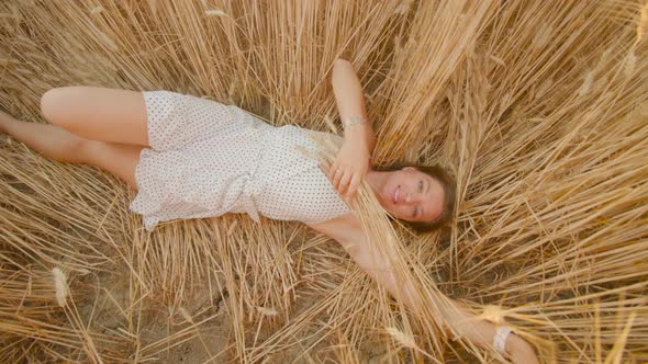 Happy Woman in Frock Rests in Flattened Golden Ripe Field