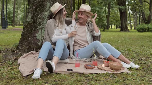 Daughter Putting Hat on Her Mom during Picnic