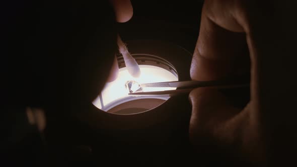 A gemologist inspecting a large clear diamond under a microscope
