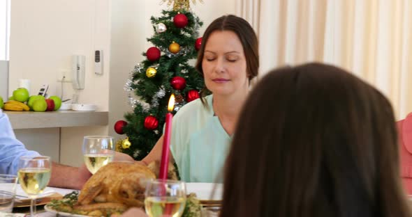 Extended family saying grace before christmas dinner 4k