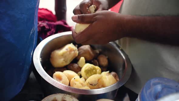 An unrecognizable man peeling potatoes at a street food stall in India, Asia, Slow motion, Close up