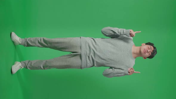 Full Body Of Asian Man Pointing Up While Standing In Front Of Green Screen Background