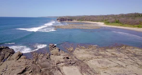 Aerial drone view of the beach, rocks and tide pools in Playa Palada, Guiones, Nosara, Costa Rica