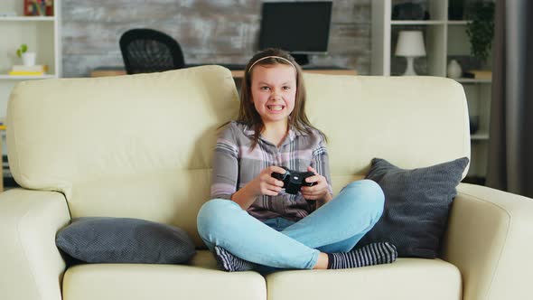 Cheerful Little Girl Playing Video Games Using Wireless Controller