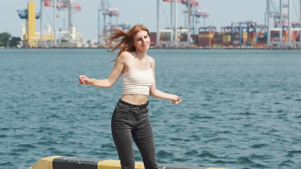 Young Stylish Funky Red Haired Girl Dancing Near Sea Port During Sunny Day