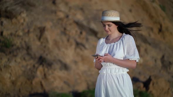 Tourist Woman Look at the Cellphone and Stand at the Seaside