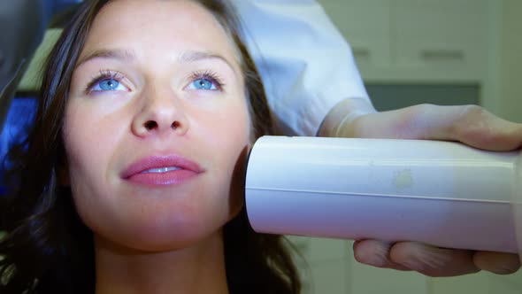 Dentist examining a female patient with dental tool