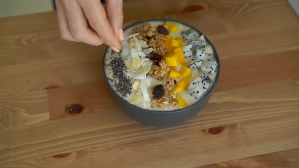 Slowmotion Shot of a Young Woman Cooking Banana Smoothie Bowl with Dragon Fruit, Mango, Granola