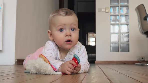 Sweet Blue-eyed Baby Girl with Toy on the Floor at Home