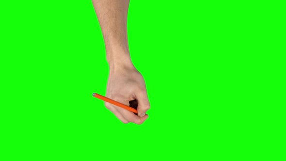 Male Hand with Orange Pencil Is Writing on Green Screen Background