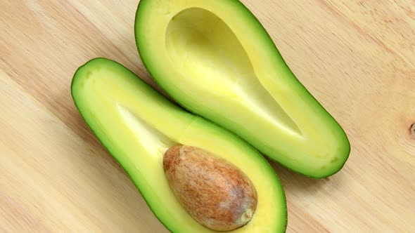 Two Half of Avocado Rotating Top View on Wooden Background