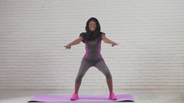 African Woman Doing Squats on Mat