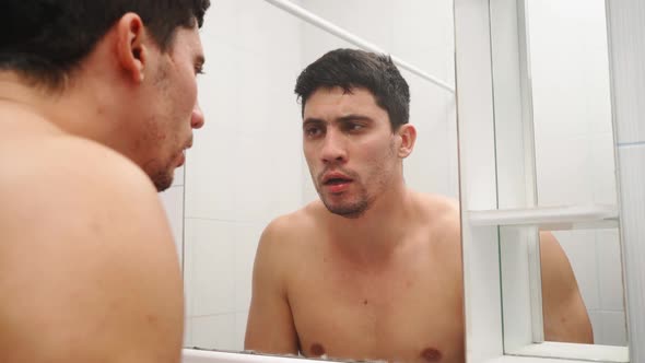 Tired Man with Stubble on His Face Washes in Bathroom and Look Himself in Mirror