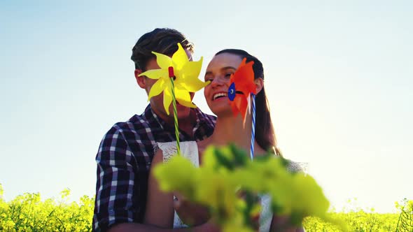 Romantic couple blowing pinwheel in mustard field