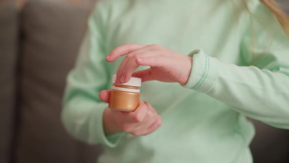 Child Opens Golden Paint Bottle By Sofa in Living Room