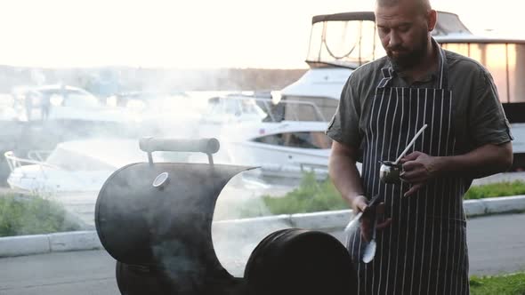 Man roasts of meat on grill and greases it with oil. barbecue grill outside