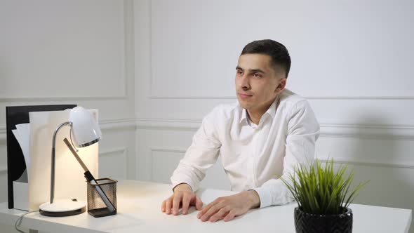 Office Employee Young Man Is Procrastinating Sitting at Work at the Office Table