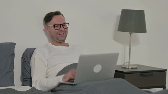 Casual Man Doing Video Call on Laptop in Bed