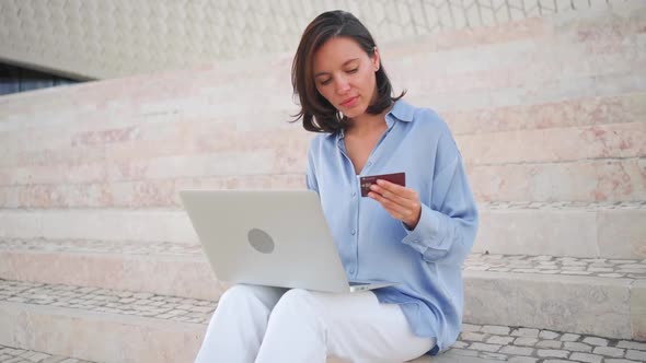 Business Woman Making Online Payment on Laptop Sitting Stairs Outdoors