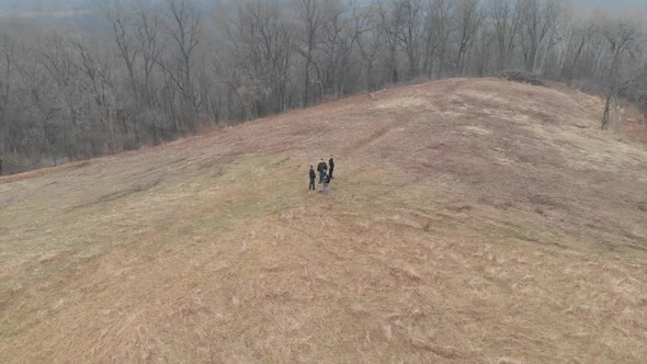 aerial footage spinning in circle of people on a dry pastureland, trees around