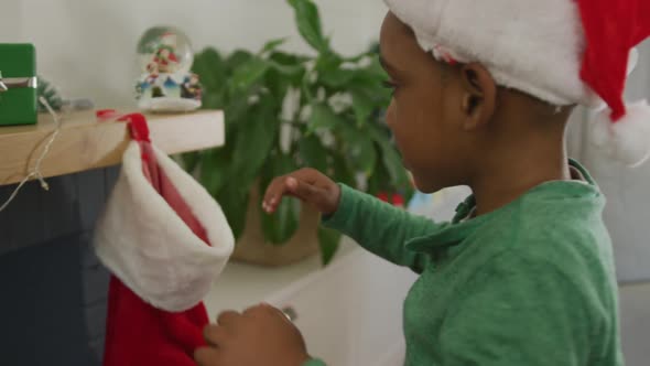 Animation of african american boy searching for present in stocking at christmas time